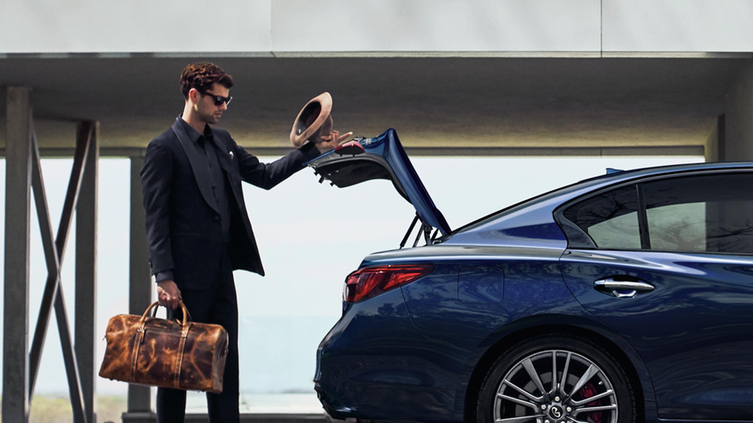 A man opening the trunk of a 2022 INFINITI Q50 sedan.